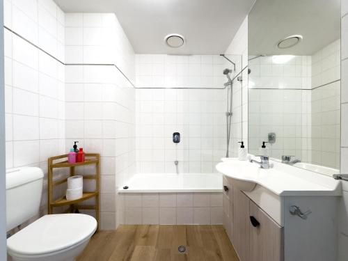 a bathroom with a tub and a toilet and a sink at Ocean view apartment close to CBD with indoor pool. in Melbourne