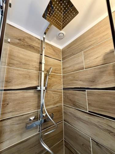 a shower with wooden walls and a shower head at La Halte - T2 centre de Tinteniac in Tinténiac