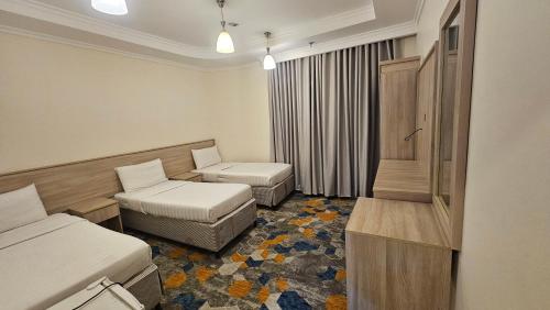 una piccola stanza con due letti e una sedia di فندق ربوة الصفوة ريع بخش a Ajyad