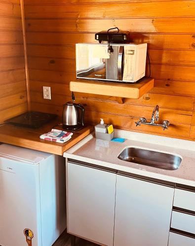 a kitchen with a sink and a microwave at Pousada Recanto do Lago in Cambará