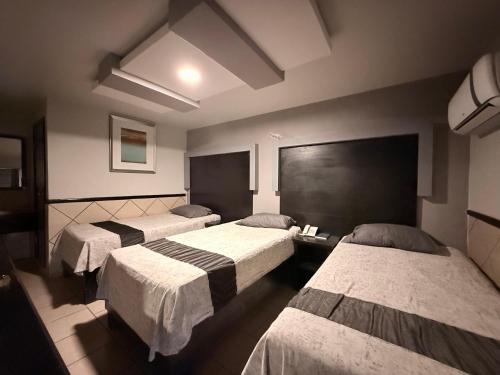 a hotel room with three beds in it at Hotel Las Vegas in Matamoros