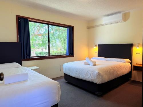 a hotel room with two beds and a window at Leski Club in Jindabyne