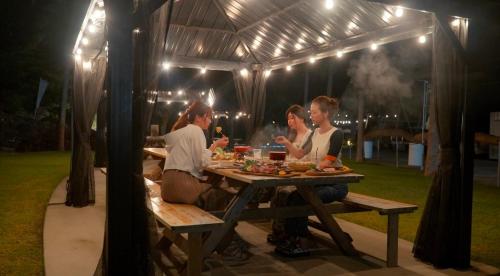 MatsuuraGlamping village Seagrand的一群人晚上坐在野餐桌旁