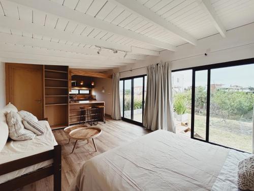 een slaapkamer met een bed, een bureau en ramen bij Casa Franca in José Ignacio