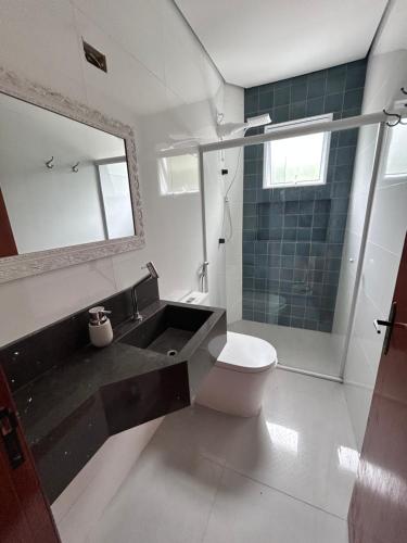 ein Badezimmer mit Waschbecken, Toilette und Spiegel in der Unterkunft Apartamento Charmoso com Mezanino em Juquehy in São Sebastião