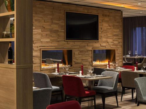 een restaurant met tafels en stoelen en een televisie aan de muur bij Mercure Hotel Amsterdam West in Amsterdam