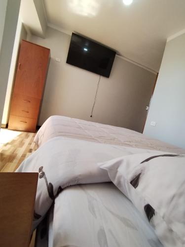 a bedroom with a bed and a tv on the wall at La Merced in Juliaca
