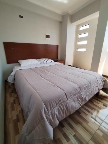 a bedroom with a large bed with a wooden headboard at La Merced in Juliaca