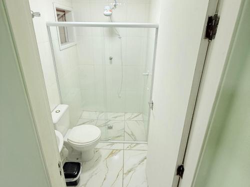 un bagno bianco con doccia e WC di Golden Garden Hostel a Ubatuba