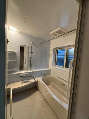 a bathroom with a tub and a sink and a mirror at Riverside Garden -kumanokodo-chikatsuyu- in Tanabe