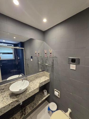 a bathroom with a sink and a toilet and a mirror at Flat Privativo Rua das Pedras in Búzios