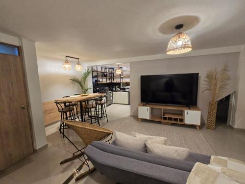 a living room with a couch and a tv and a table at Casa Vacacional para 15 Personas con Jacuzzi Privado A 20 min de Salento by Molca Travel in Armenia