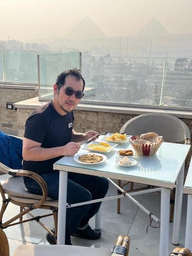 Ein Mann, der an einem Tisch mit einem Teller Essen sitzt. in der Unterkunft Grand museum & pyramids view inn in Banī Ghālib