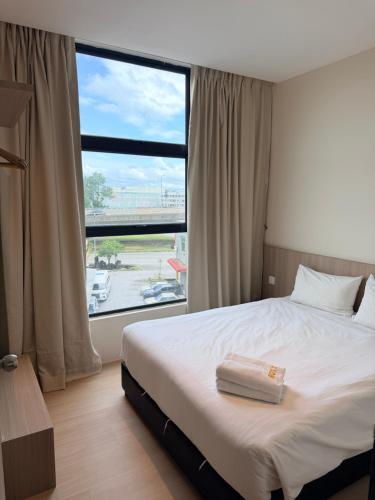 a bedroom with a bed and a large window at Roxy Hotel 3rd Mile in Kuching