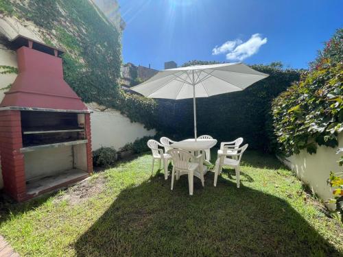 a table and chairs with an umbrella in the grass at Casa Storni in Mar del Plata