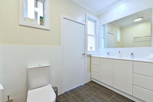a bathroom with a toilet and a sink and a mirror at Glandore Estate in Pokolbin
