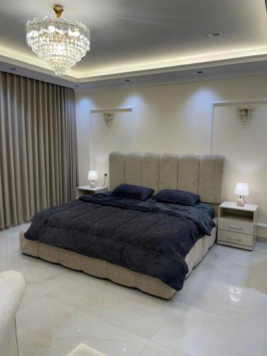 una camera da letto con un letto grande e un lampadario di جوهرة العزيزية a Dhahran