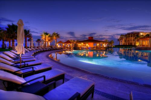 a swimming pool with chairs and umbrellas at night at The Towers at Pueblo Bonito Pacifica - All Inclusive - Adults Only in Cabo San Lucas