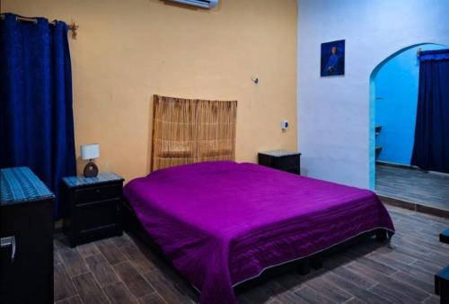 a purple bed in a room with blue curtains at La casa azul en Ticul Yucatán in Ticul