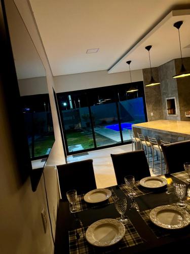 a dining room with a table and chairs and windows at casa com piscina in Sinop