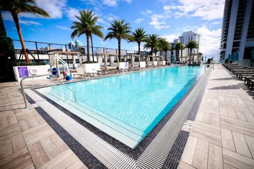 a large swimming pool with chairs and palm trees at Penthouse Ocean Front View Mansion in Sky Corner in Hollywood