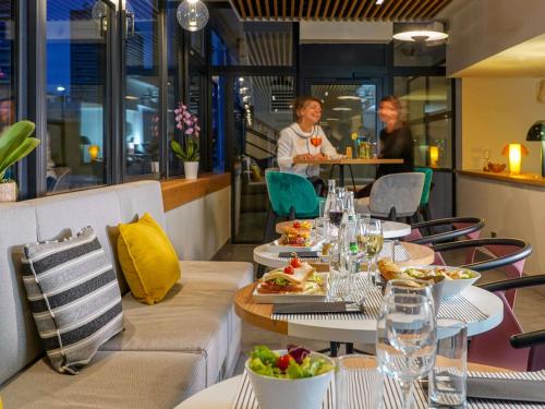 een restaurant met tafels met eten en mensen op de achtergrond bij Mercure Marseille Centre Prado Vélodrome in Marseille