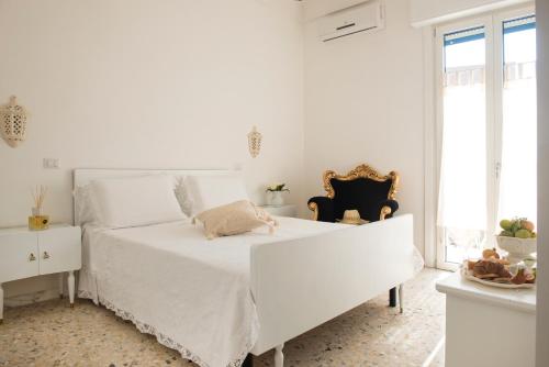 um quarto branco com uma cama branca e uma janela em Dimora Cappuccini Guest House em Cisternino