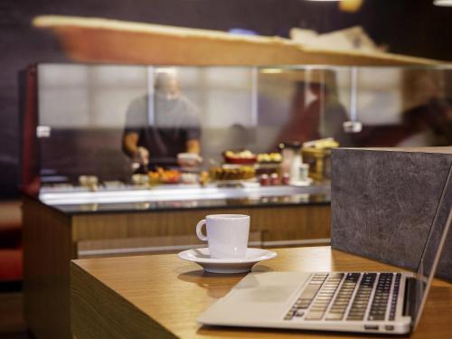 a laptop computer sitting on a table with a coffee cup at ibis Sao Jose dos Campos Dutra in São José dos Campos