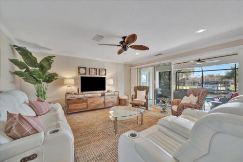 a living room with white furniture and a flat screen tv at Siesta Key Beach Waterfront Home with Kayaks and Bikes in Siesta Key