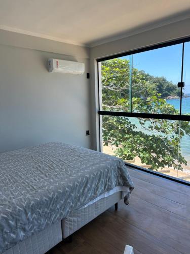 a bedroom with a bed and a large window at Duplex beira mar ilha grande proveta in Angra dos Reis