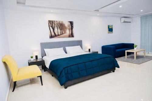 a bedroom with a bed and a yellow chair at Tris Estates Hotel & Suites in Dwarzohn