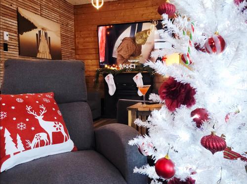un albero di Natale bianco in un soggiorno con sedia di Domaine pour 21 pers avec SPA et GRANGE Festive a Saint-Justin