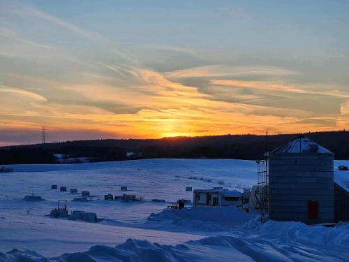 a sunset over a snow covered field with a building at Domaine pour 21 pers avec SPA et GRANGE Festive in Saint-Justin