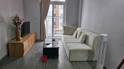 ein Wohnzimmer mit einem weißen Sofa und einem Fernseher in der Unterkunft DINO Home HACOM 2BR city center in Kinh Dinh