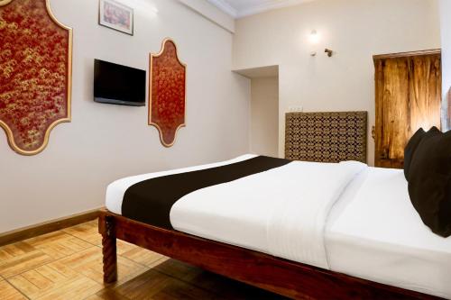 a bedroom with a bed and a tv on the wall at Collection O Rai Ka Bagh Near Railway Station Formerly Pioneer Plaza in Jodhpur