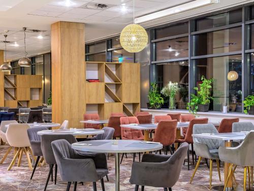 un ristorante con tavoli, sedie e finestre di Novotel Kraków Centrum a Cracovia