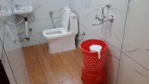 ein Badezimmer mit Toilette und rotem Mülleimer in der Unterkunft Tree Heaven Homestay in Chamba