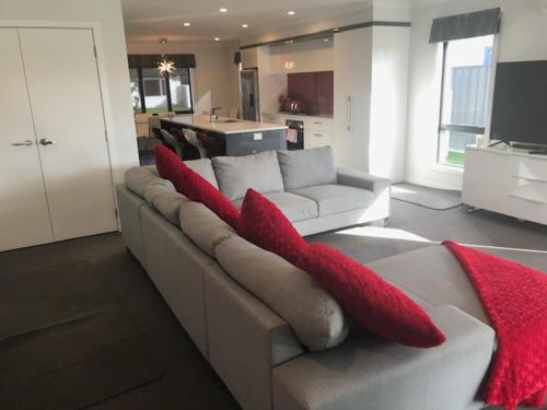 a living room with a couch with red pillows on it at Parklands paradise 3bedroom4beds in Napier