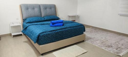 een slaapkamer met een bed met een blauwe deken en kussens bij Sireh Residence in Kota Bharu