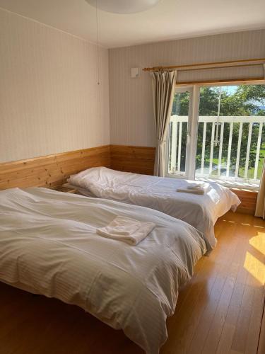 two twin beds in a bedroom with a window at aomame villa lake toya in Lake Toya