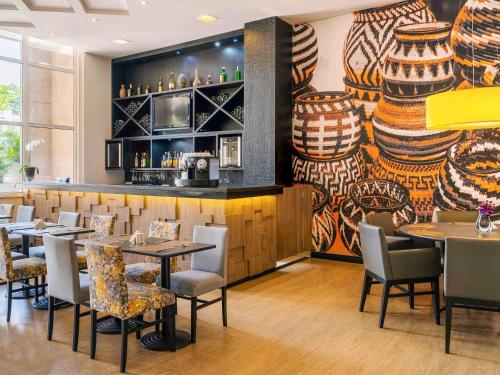 Un restaurante con mesas y sillas y un bar. en Mercure Guarulhos Aeroporto, en Guarulhos