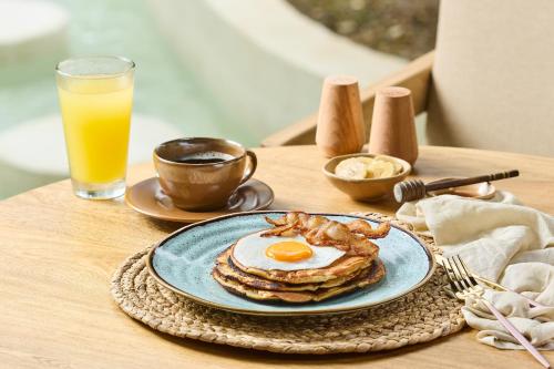 a plate of pancakes with an egg and bacon on a table at Holistic EcoHotel in Santa Fe de Antioquia