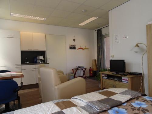 a room with a bed and a kitchen with a television at B & B Leudal in Haelen