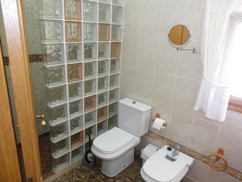 a bathroom with a toilet and a glass block wall at Azahara in Lloret de Mar