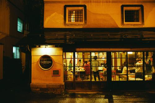 a group of people standing outside a restaurant at night at Hostel&Bar CAMOSIBA in Yokote
