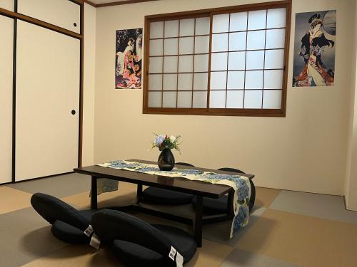 een kamer met een tafel en stoelen met een vaas erop bij Shinehouse2 in Kawaguchi