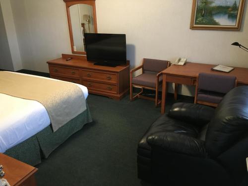 a hotel room with a bed and a television and a chair at Garden Inn and Suites Fresno in Fresno
