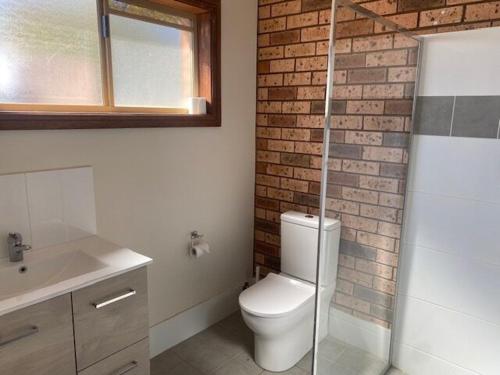 a bathroom with a toilet and a brick wall at Lucky Strike Motel in Tomingley