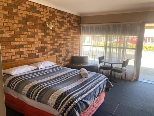 a bedroom with a bed and a brick wall at Lucky Strike Motel in Tomingley