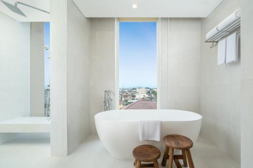 een badkamer met een groot bad en 2 krukken bij ARTOTEL Leguna Magelang in Magelang